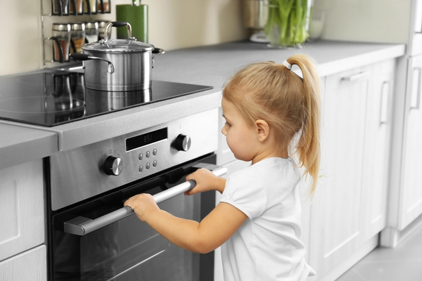 Little girl playing with oven in kitchen - 写真・画像