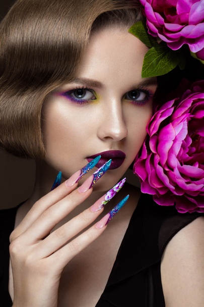 Beautiful girl with colorful make-up, flowers, retro hairstyle and long nails. Manicure design. The beauty of the face. - Photo, image