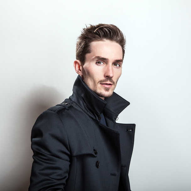 Elegant young handsome man in long stylish dark blue coat. Studio fashion portrait. - Photo, Image