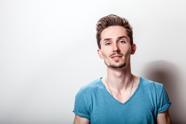 Studio portrait of young handsome man in casual turquoise t-shirt. - 写真・画像