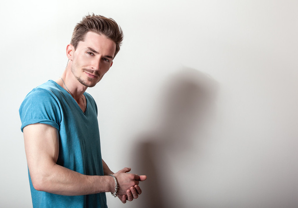 Studio portrait of young handsome man in casual turquoise t-shirt. - Photo, image