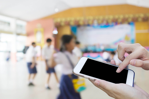 Kobieta za pomocą ekran dotykowy telefon z blur student playi - Zdjęcie, obraz