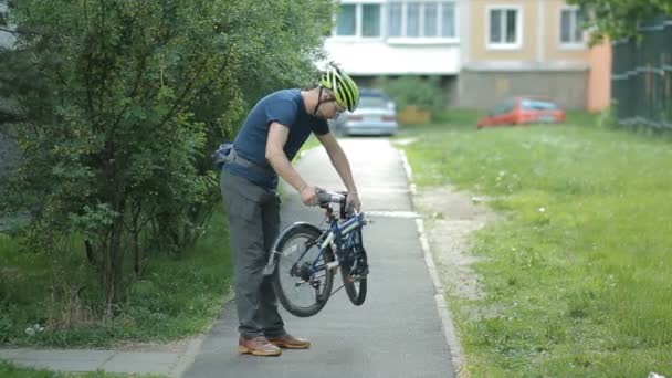 Man with beard folding bicycle near home - Video, Çekim