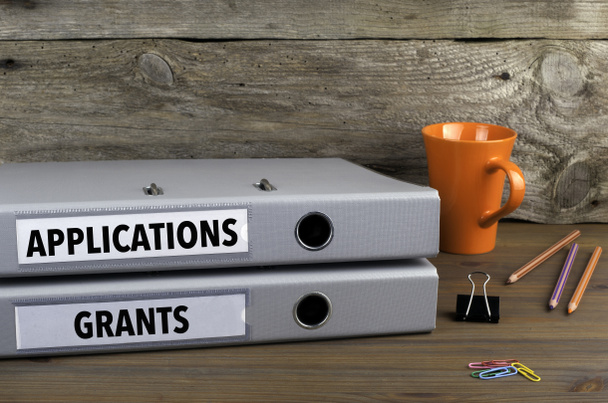 Applications and Grants - две папки на деревянном рабочем столе
 - Фото, изображение