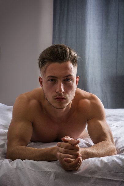 Shirtless sexy male model lying alone on his bed - Фото, зображення