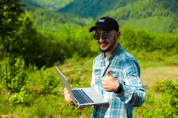 male model working in the mountains on a laptop - Фото, зображення