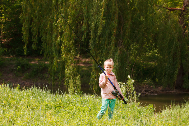 Photo of little kid pulling rod while fishing on weekend - Foto, afbeelding