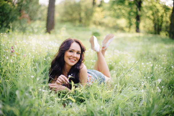 zonnige zomerdag, een mooie jonge vrouw liggend op het gras - Foto, afbeelding