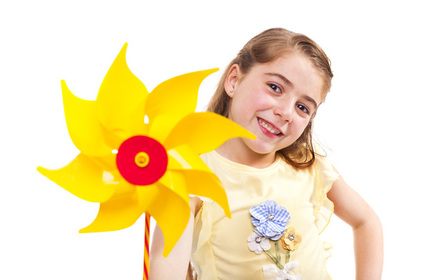 Smiling girl holding a yellow pinwheel - Фото, изображение
