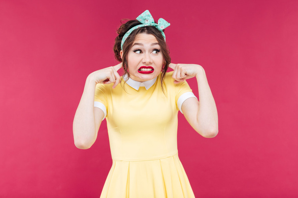 Cute irritated pinup girl closed her ears by fingers - Foto, Imagem