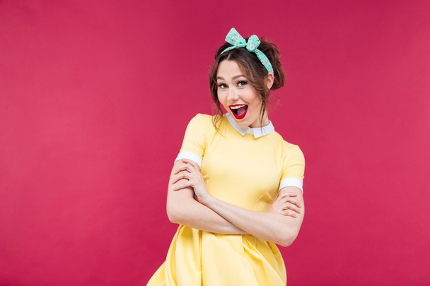 Happy pinup girl in yellow dress standing with arms crossed - Foto, imagen
