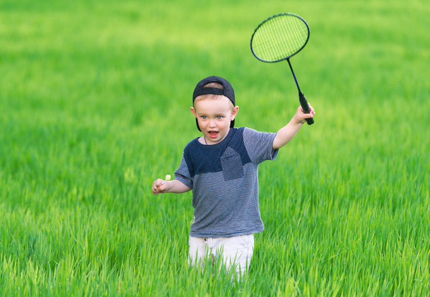 The little boy in cap plays in grass. - Φωτογραφία, εικόνα