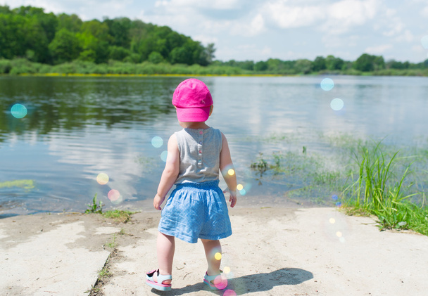 Κοριτσάκι σε ροζ ΚΓΠ κόστος στην όχθη της λίμνης. - Φωτογραφία, εικόνα