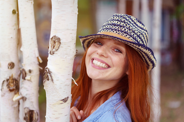 Cute red haired woman in hat beside birch trees - Fotografie, Obrázek