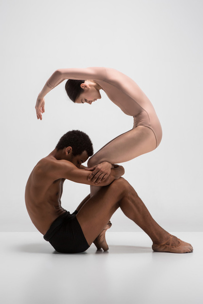 Couple of ballet dancers posing over gray background - Photo, image