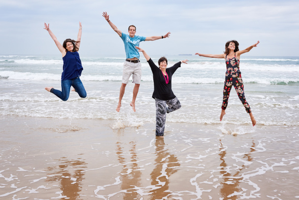 Ευτυχισμένη οικογένεια πηδούν όλοι μαζί πάνω στην παραλία στο τοπίο - Φωτογραφία, εικόνα