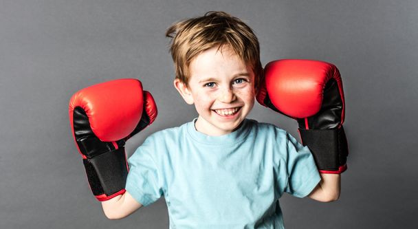 happy young boy with freckles holding big boxing gloves - Φωτογραφία, εικόνα