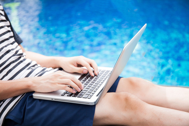Man using a laptop in the pool on vacation - work anywhere and internet work concept - Foto, immagini