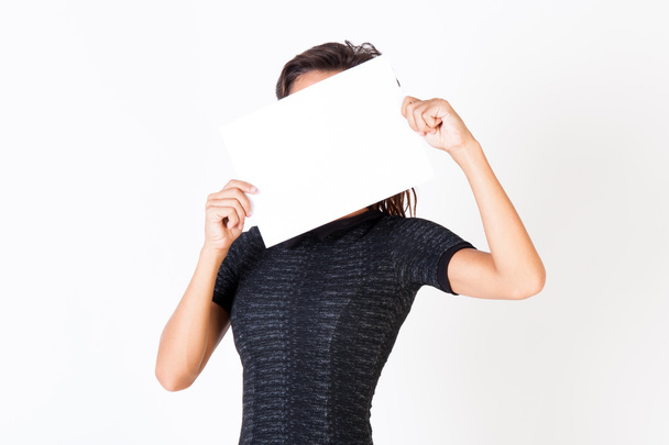 Uma bela mulher segura um papel em branco e esconde seu rosto isolado no fundo branco
 - Foto, Imagem