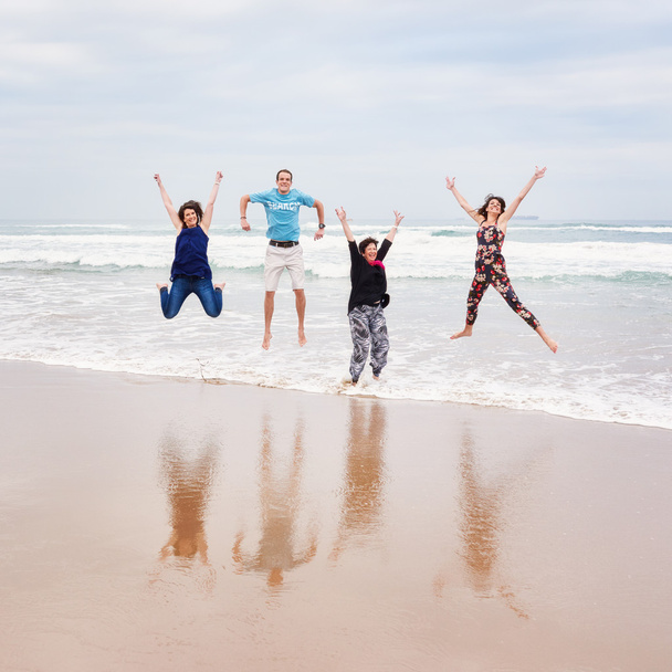 Квадратне зображення сім'ї, що стрибає на пляжі
 - Фото, зображення