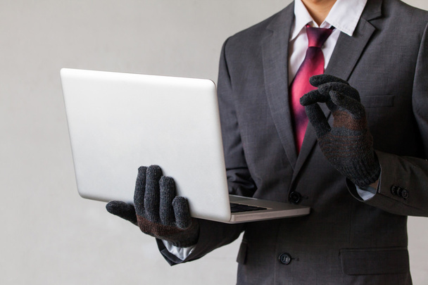 Zakenman, het dragen van handschoenen en het gebruik van computer - hacker, diefstal, fraude, cyber crime concept - Foto, afbeelding