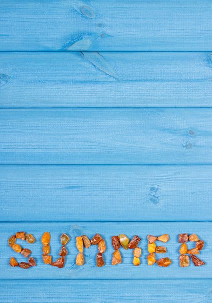 Word summer made of amber stones on blue boards, summer time, copy space for text - Fotoğraf, Görsel