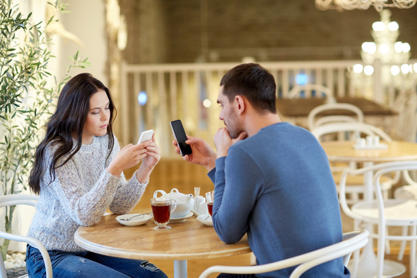 couple with smartphones drinking tea at cafe - Фото, изображение