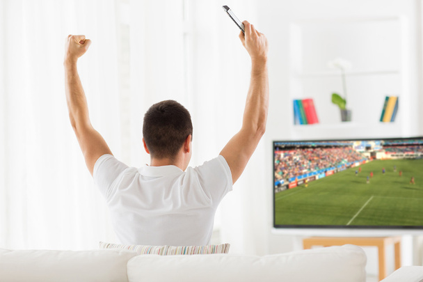 happy man watching football or soccer game on tv - Foto, afbeelding