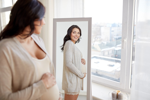 happy pregnant woman looking to mirror at home - Fotografie, Obrázek