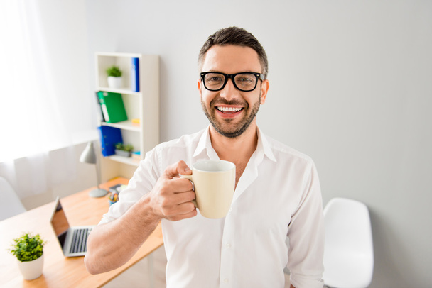 Portrait of smiling happy businessman in glasses holding cup of  - Fotó, kép