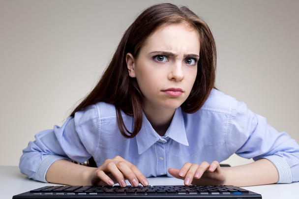 Frowning woman using keyboard - Фото, изображение