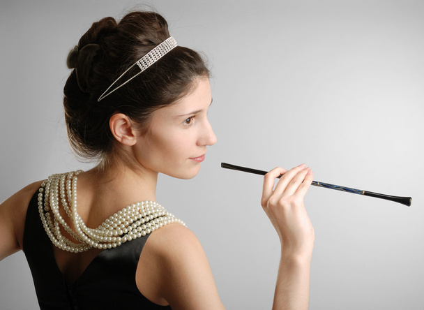 Elegant girl with cigar-holder, side view - Фото, изображение
