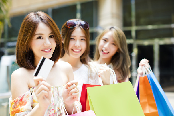 onnellinen nuori naiset osoittavat ostoskassit ja luottokortti
 - Valokuva, kuva