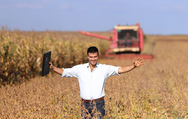 Agricultor con cosechadora en campo de soja
 - Foto, Imagen