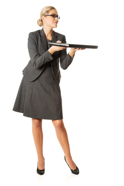 Businesswoman standing and holding a laptop - Fotó, kép