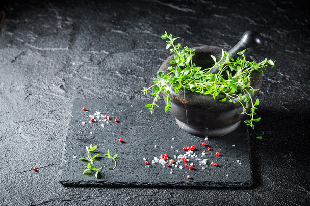 Argamassa com sal, pimenta e tomilho em rocha preta
 - Foto, Imagem