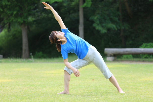 Japanese woman outside doing yoga triangle pose - 写真・画像