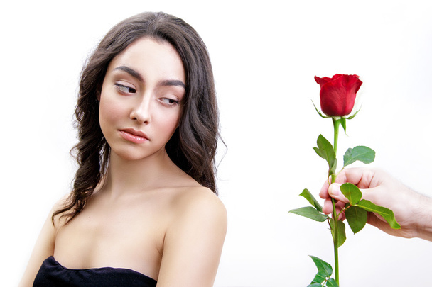 Beautiful angry girl receives one red rose. She is surprised, looking at the flowers and starts smiling.  - Foto, Imagem