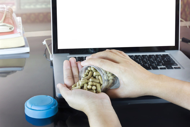 Hand and moringa capsules with blank screen notebook or computer - Photo, Image