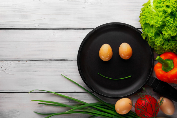 Smiling face from eggs on frying pan.Salad. sweet pepper, green  - Foto, immagini