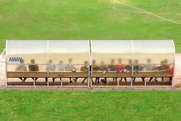 Fotbaloví hráči a zaměstnanci sedět na lavici vedle fotbalové hřiště (Away team) - Fotografie, Obrázek