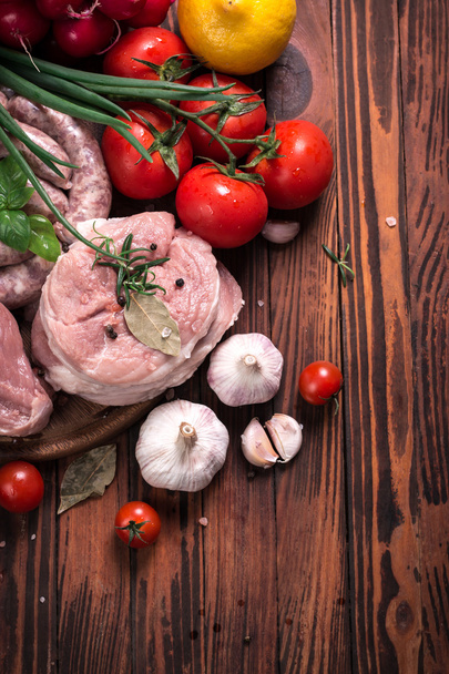 Fresh butcher cut meat assortment garnished with fresh rosemary on wooden table - Фото, зображення