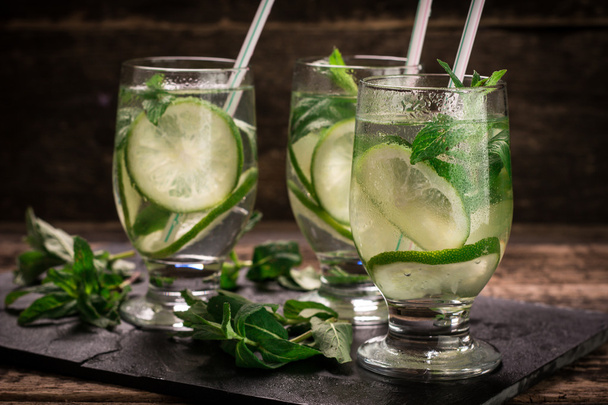detox water with a lemon, lime and mint on a wooden table - Fotoğraf, Görsel