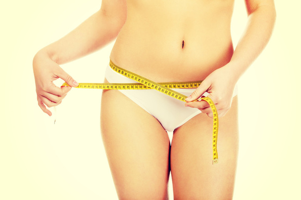 Beautiful slim woman measuring her hips - Foto, Bild
