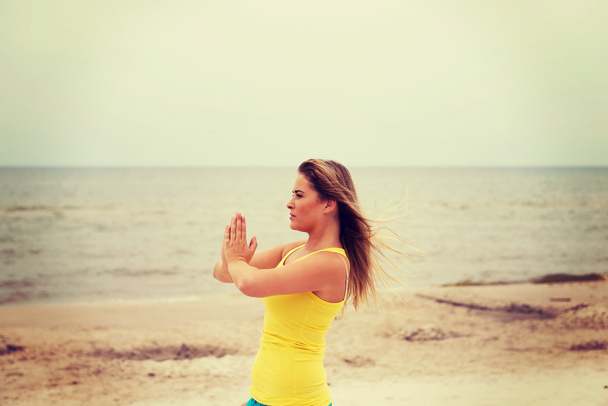 Jeune femme faisant des exercices de yoga sur la plage
 - Photo, image