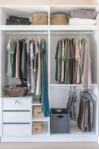 roupas e vestido pendurado no trilho no armário branco
 - Foto, Imagem