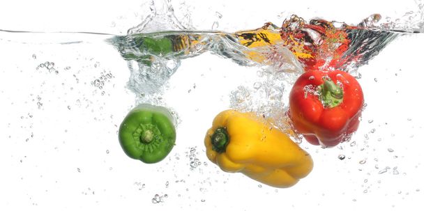 Three peppers falling into water, over white background - Foto, Imagen