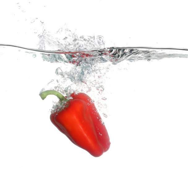 κόκκινο πιπέρι που πέφτουν στο νερό λευκό φόντο - Φωτογραφία, εικόνα