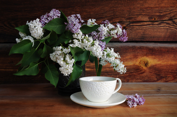bouquet of lilac and a mug of tea - Photo, Image