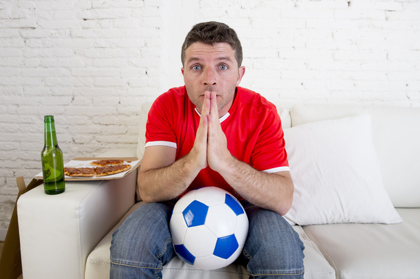 young man watching football game on tv nervous and excited suffering stress praying god for goal - 写真・画像